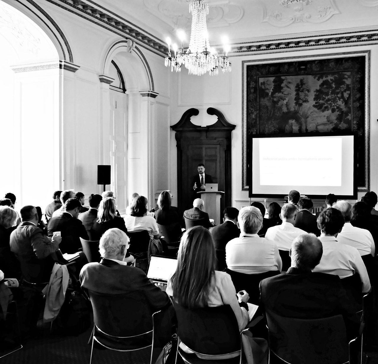Caetano Penna giving a keynote at the Babbage Forum 2026 in Cambridge, seen from the back of a full room